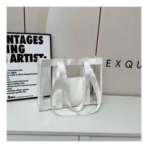 Detail of transparent PVC tote bag with white nylon straps and inner pouch on white surface