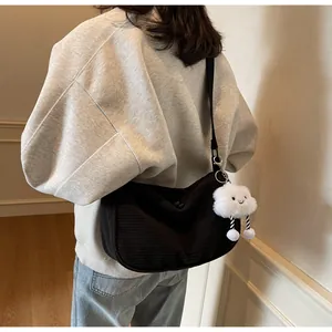 Detail view of black corduroy half-moon crossbody bag with cute plush cloud charm