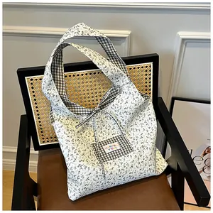 Detail of floral tote bag with bow accent and plaid pocket on a vintage chair