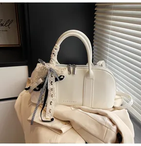 Detalle de bolso bandolera de cuero blanco con grabado CLEAR y lazo de encaje suave