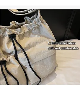 Detail of cream nylon crossbody bag featuring drawstring closure and pleated texture