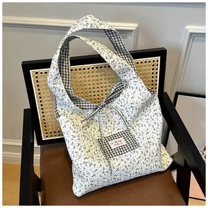 Detail of floral and checkered canvas tote bag with bow accent on a vintage chair