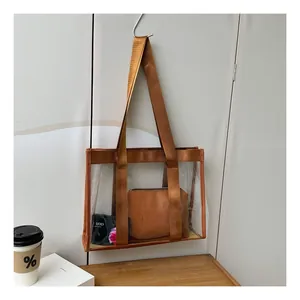 Detail view of transparent PVC tote bag with brown fabric straps and inner leather pouch