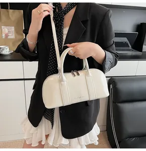 Detalle del bolso boston de cuero sintético blanco crema con herrajes plateados en oficina