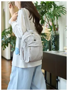 Macro detail of the light grey nylon backpack with multi-layer zippers and side pocket