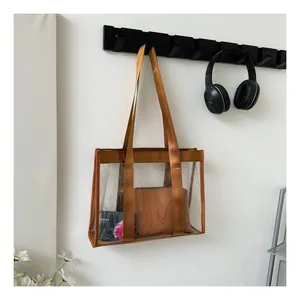 Detail view of transparent jelly tote bag with brown straps and matching inner pouch