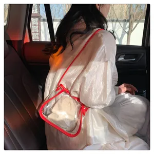 Detailed shot of transparent PVC crossbody bag with red trim and a beige inner pouch