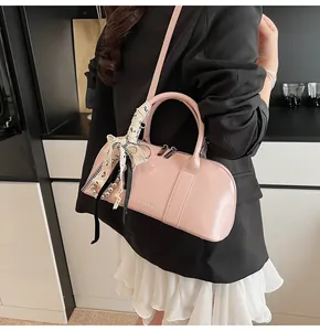 Detalle de bolso rosa en cuero sintético con lazo de encaje y colgante de perlas