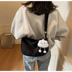 Detail showing black corduroy crossbody bag texture and plush cloud keychain on model