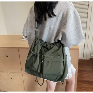 Army green nylon crossbody bag with drawstring closure and large front pockets on a model