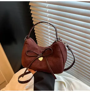 Detailopname van de bruine suède textuur en het hartvormige metalen label op de tas