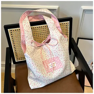 Pink floral tote bag with gingham pockets and bow detail on a vintage chair