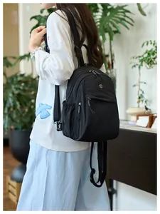 Detail view of the black nylon mini backpack showing the side pocket and metal logo detail