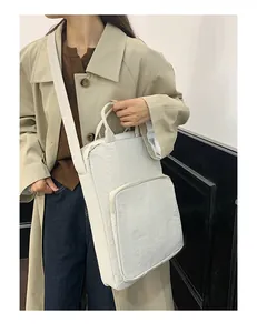 Detail view of cream oxford fabric tote bag with large front zipper pocket on model