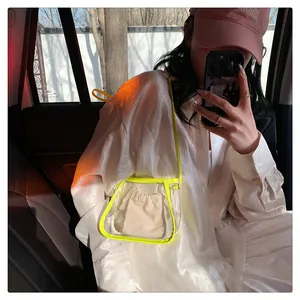 Detail of transparent PVC crossbody bag with neon yellow trim and linen drawstring pouch