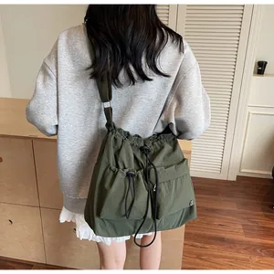 Detail of army green nylon crossbody bag with drawstring pockets and wide strap
