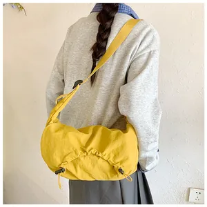Dettaglio della borsa a tracolla in nylon giallo con coulisse e fondo plissettato