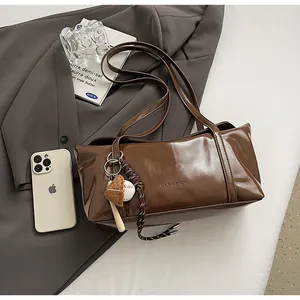 Detail of dark brown leather tote bag with GLEARSY logo and baseball glove charm