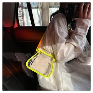 Detail of transparent PVC crossbody bag with neon yellow trim and inner drawstring pouch