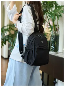 Close-up of lightweight black nylon mini backpack featuring a metal logo and adjustable straps