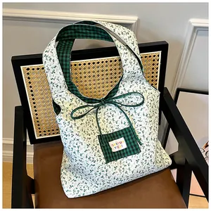 Detailed close-up of floral tote bag with green gingham lining on a vintage wicker chair