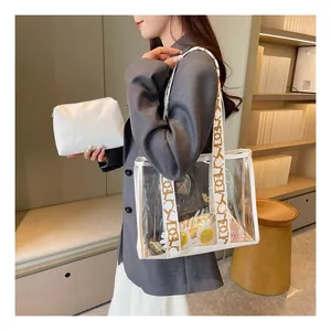 Detailed view of a transparent PVC tote bag with a wide lettered strap and inner pouch