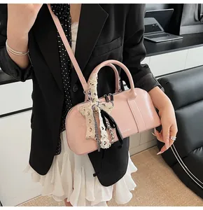 Detalle del bolso Boston rosa claro con colgante de encaje y perlas y logo EAR♥K blanco