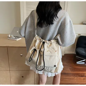 Detail shot of the beige nylon crossbody bag with pleated texture and drawstring