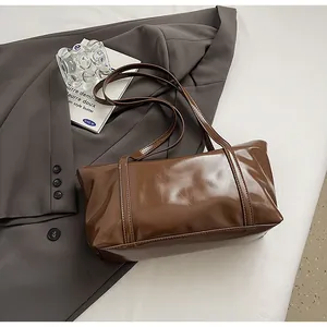 Close-up of chocolate brown oil wax leather bag texture on elegant grey blazer