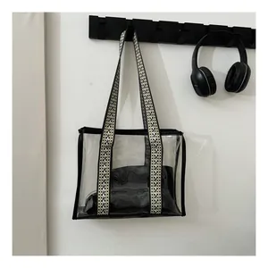 Detail of transparent PVC tote bag featuring black trim and woven herringbone handles