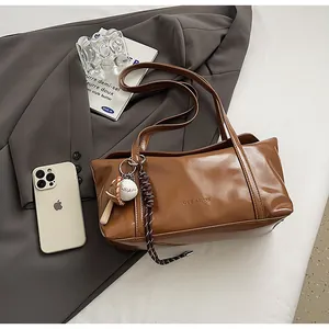 Detailed top view of a brown oil wax leather shoulder bag with chic baseball charm and straps