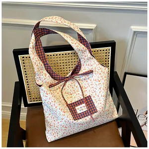 Detailed close-up of a floral canvas tote bag with a checkered lining and a bow tie closure