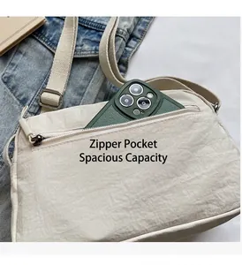 Detail of minimalist beige nylon crossbody bag with front zipper pocket and strap