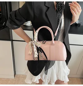 Detalle del bolso Boston de cuero rosa con lazo de encaje crema y colgante de perlas