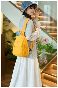 Bright yellow waterproof nylon backpack on model showing side view and shoulder straps