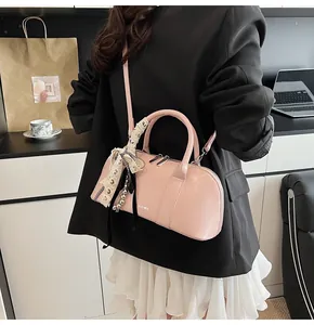 Bolso bandolera rosa estilo bowling con lazo de encaje en un entorno de oficina moderno