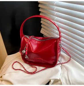 Detail of red glossy leather bag with silver chain strap and fashionable zip closure