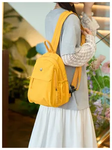 Side view of a bright yellow waterproof backpack with metallic logo and side pocket