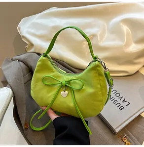 Detail van de vintage grasgroene suède handtas met decoratieve strik en hartvormige hanger
