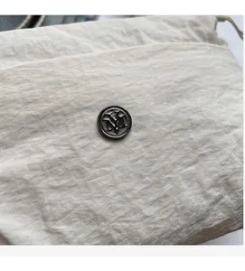 Detail of minimalist square bag with textured cream leather and VM metal buckle