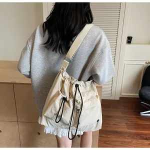 Detail of beige nylon crossbody bag featuring drawstring pockets and pleated texture design