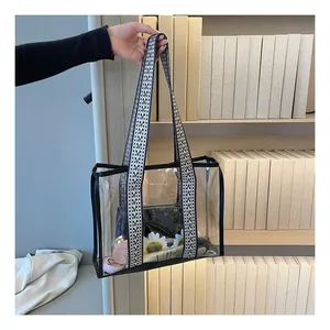 Detail of transparent PVC tote bag with black edge trim and wide geometric shoulder strap
