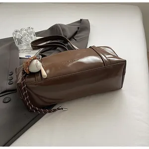 Detail of dark brown wax leather bag with GLANCOK logo and baseball pendant decor