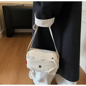 Detail der cremeweißen Umhängetasche aus Nylon mit verstellbarem Gurt und Reißverschlüssen