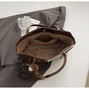 Interior view of brown tote bag showing zipper pocket, magnetic closure, and baseball charm