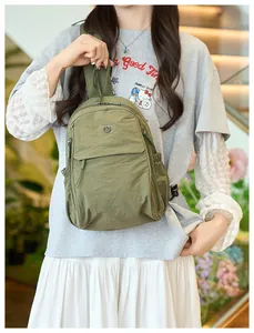 Detail view of army green nylon chest bag with metal logo on a lifestyle model