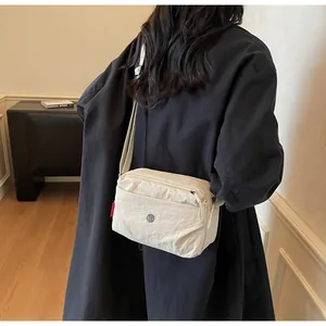Minimalistische beige Umhängetasche an Model im schwarzen Mantel in schlichter Umgebung