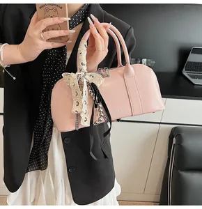 Detalle del bolso Boston de cuero rosa con asa decorada con un pañuelo de encaje