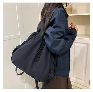 Detailopname van de grote zwarte nylon schoudertas met trekkoord en casual outfit