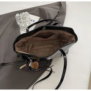 Internal view of glossy black tote bag with brown lining and secure magnetic closure